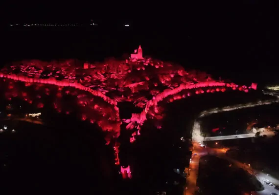 Снимка от високо на нощния спектакъл 'Звук и светлина' във Велико Търново, показваща крепостта Царевец, осветена в Червено